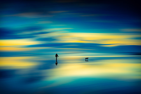 Man Walking A Dog On A Beach At Sunset